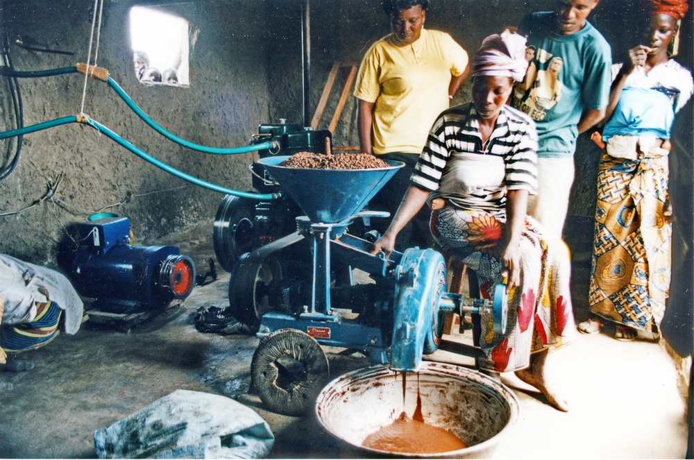 Grain grinding mill operated by a woman and watched by another women and 2 men
