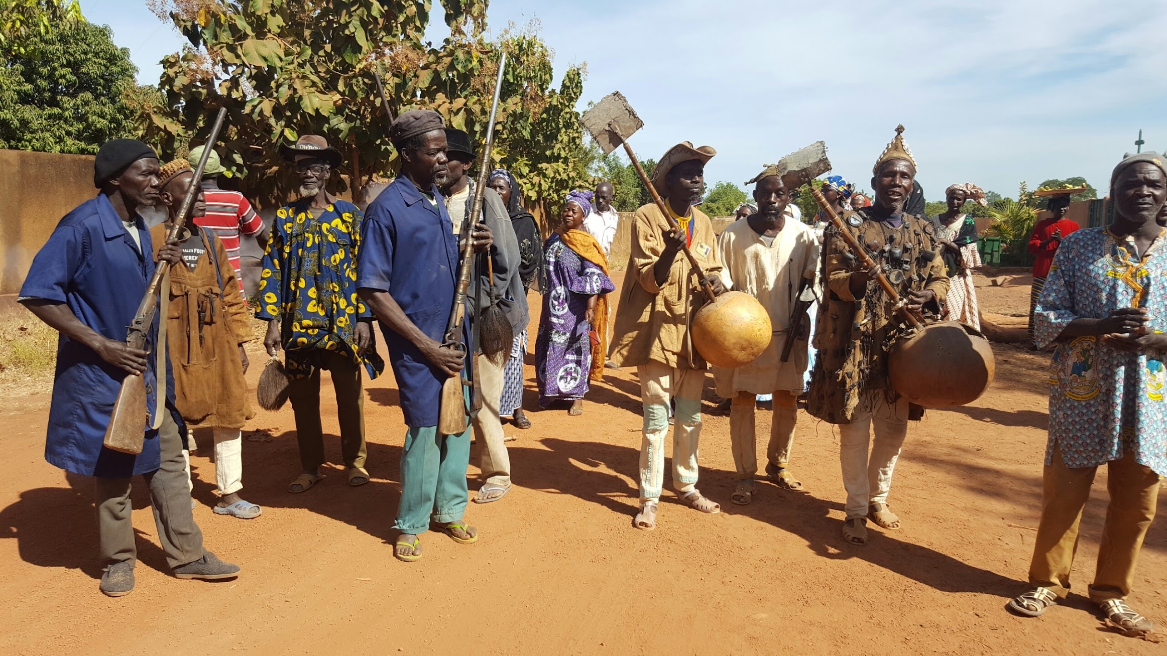 Traditional musicians with their instruments leading a village group on red dust road